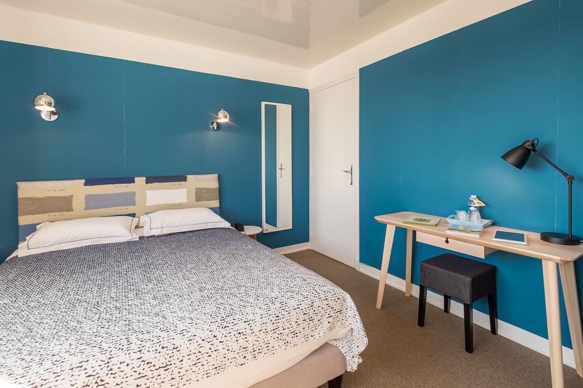 Une chambre à coucher avec un lit, un bureau, une chaise et un miroir.