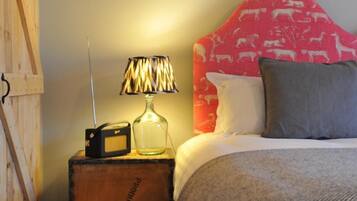 Una camera da letto con una testiera in legno, una radio su un ripiano di legno, una lampada e una coperta decorata.