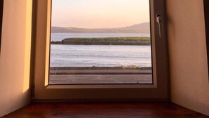 Una ventana con vista al agua y la costa lejana.