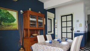 A dining room with a checkered floor, a table set with blue glassware, white chairs, and a wooden cabinet with glass doors. - Sea View Apartment (Ragusa)