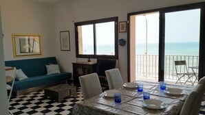 A dining area with a checkered floor, a table set for four, and a view of the sea through an open door. - Sea View Apartment (Ragusa)
