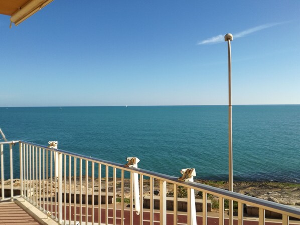 Un balcon avec vue sur la mer et un voilier qui se profile à l’horizon.