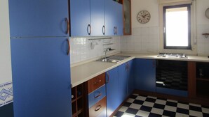 A kitchen with blue cabinets, a checkered floor, a sink, and a window. - Sea View Apartment (Ragusa)