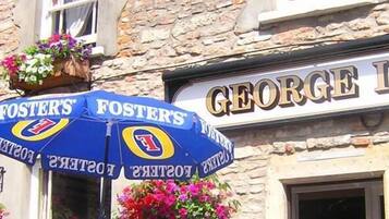 A building with a sign reading "GEORGE INN" and a blue umbrella with "FOSTER'S" branding.