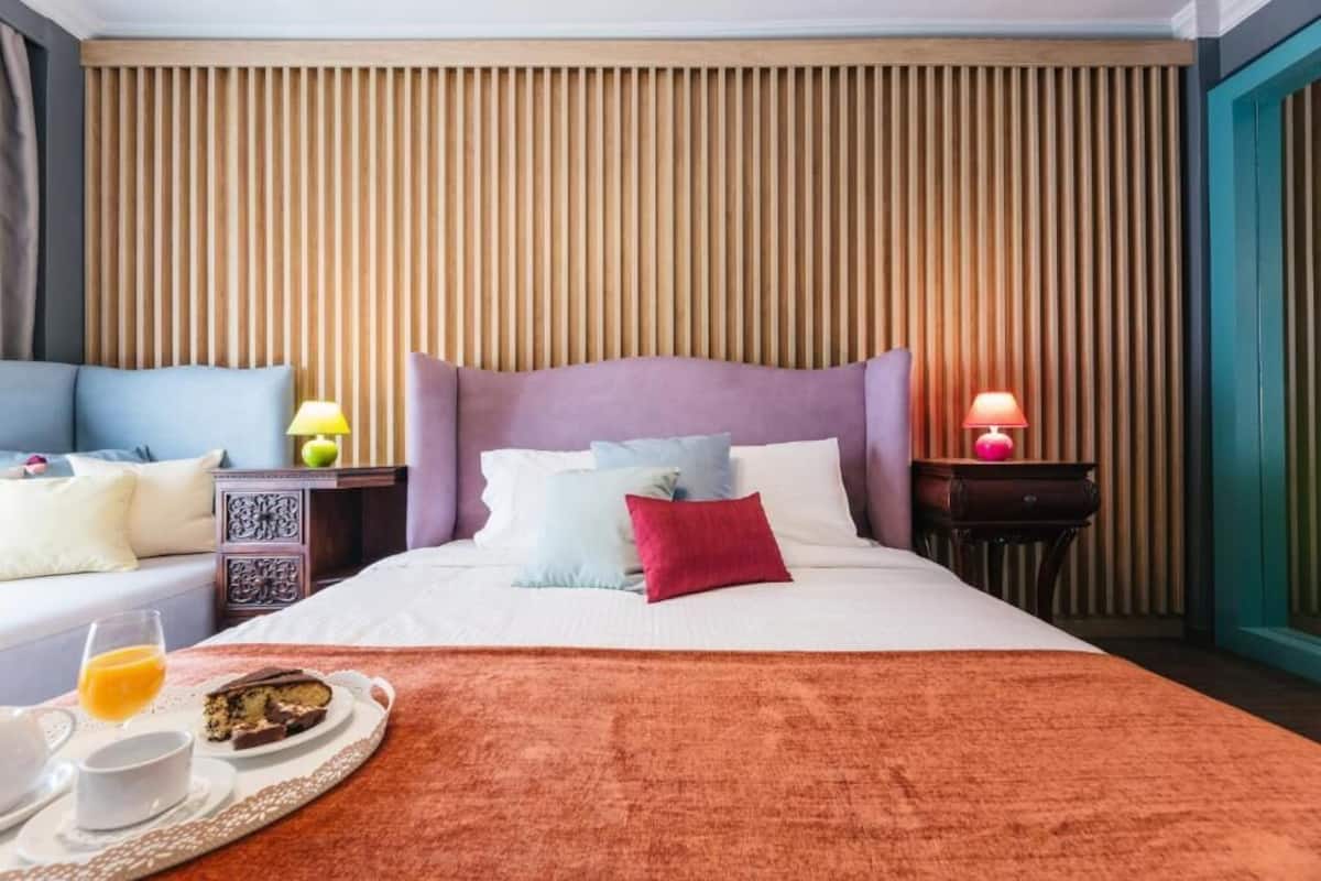 A hotel room with a bed, bedside tables, a nightstand, a tray with breakfast, and a wall with vertical wooden slats.