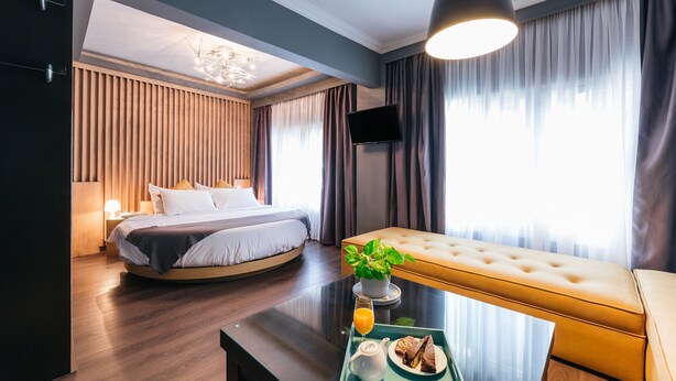 Une chambre d’hôtel moderne équipée d’un lit, d’un canapé, d’une table à manger avec un petit-déjeuner, et d’une télévision.