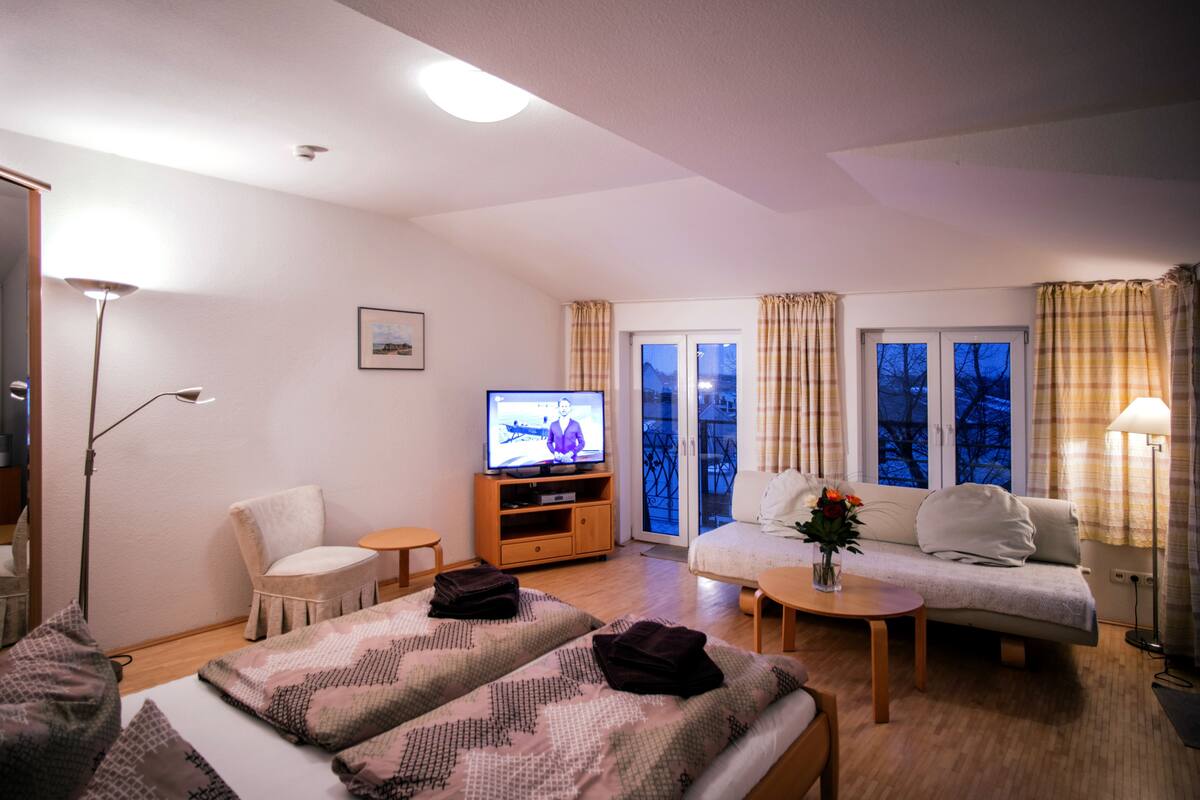 Una sala de estar moderna con un sofá, dos sillones, una mesa de centro y un televisor sobre un mueble de madera.