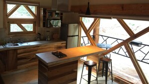 Una cucina rustica con travi in legno, un piano cottura integrato, un frigorifero e una finestra che si affaccia su un paesaggio naturale.