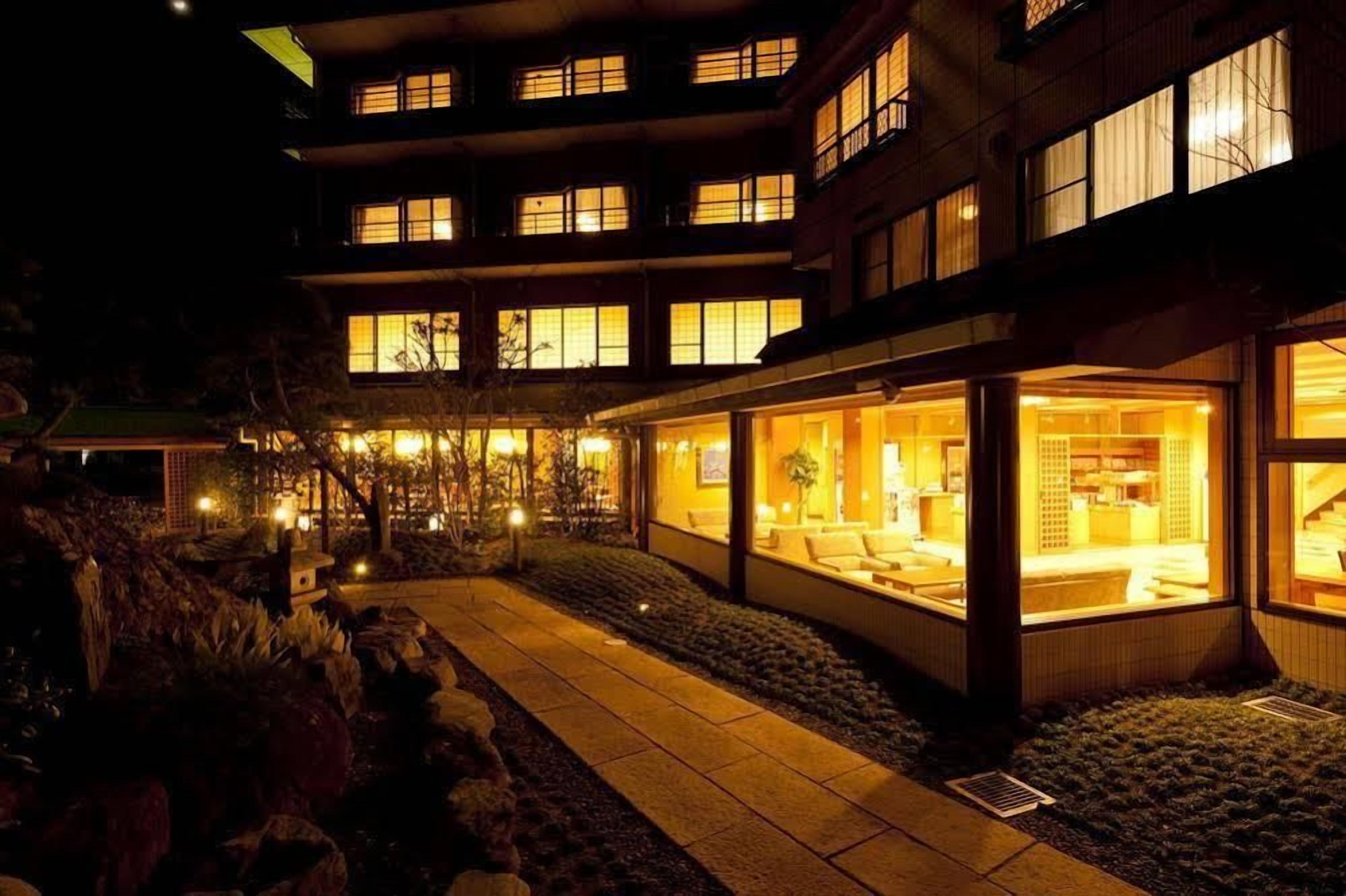 A multi-story building with illuminated windows and a well-lit interior, suggesting a hotel or residential complex.