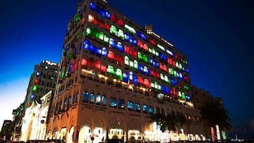 Un hotel de varios pisos con una fila de balcones, cada uno con una luz de color diferente.