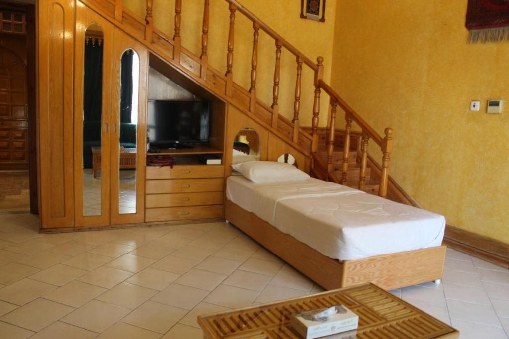 Une chambre avec un lit en bois, une armoire intégrée et un escalier.