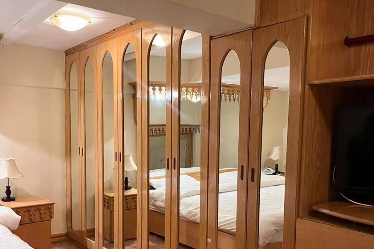 Une chambre à coucher avec une armoire en bois, un lit, une table de chevet et un téléviseur.