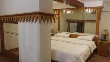 A bedroom with a large bed, a wooden headboard, a nightstand, and a mirror.