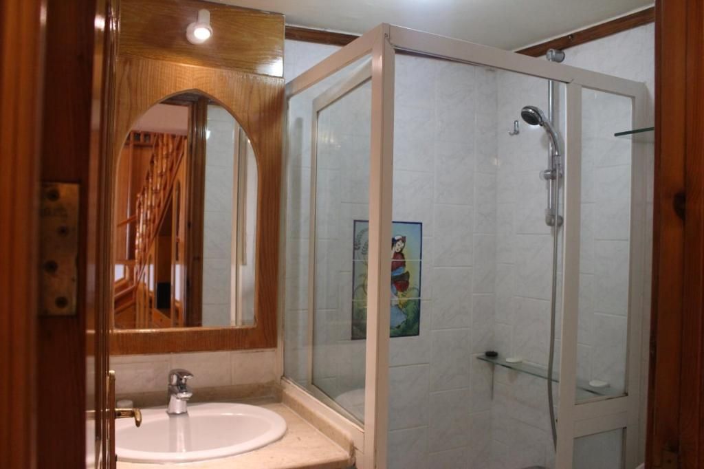 Ein Badezimmer mit einem Holzbadschränkchen, einer Glasdusche und einem gefliesten Boden.