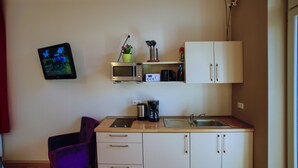 A compact kitchen with a microwave, coffee maker, and a small potted plant. - Ferienwohnungen Eicher Wachtlerstraße (Rostock)