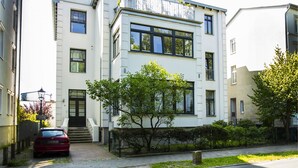 A modern two-story building with a white facade, large windows, and a visible balcony. - Ferienwohnungen Eicher Wachtlerstraße (Rostock)