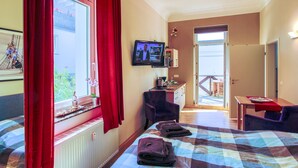 A hotel room with a bed, a desk, a television, and a view of the outside. - Ferienwohnungen Eicher Wachtlerstraße (Rostock)