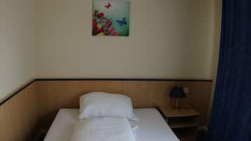 A neatly made bed with white linens, a small bedside table with a lamp, and a painting on the wall.