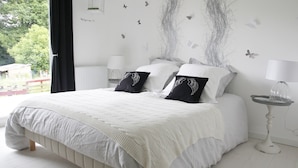 A bedroom with a large bed, two bedside tables, a window with curtains, and a wall with butterfly decals. - Chambres d'hôtes Souffle Nature  (Montenois)