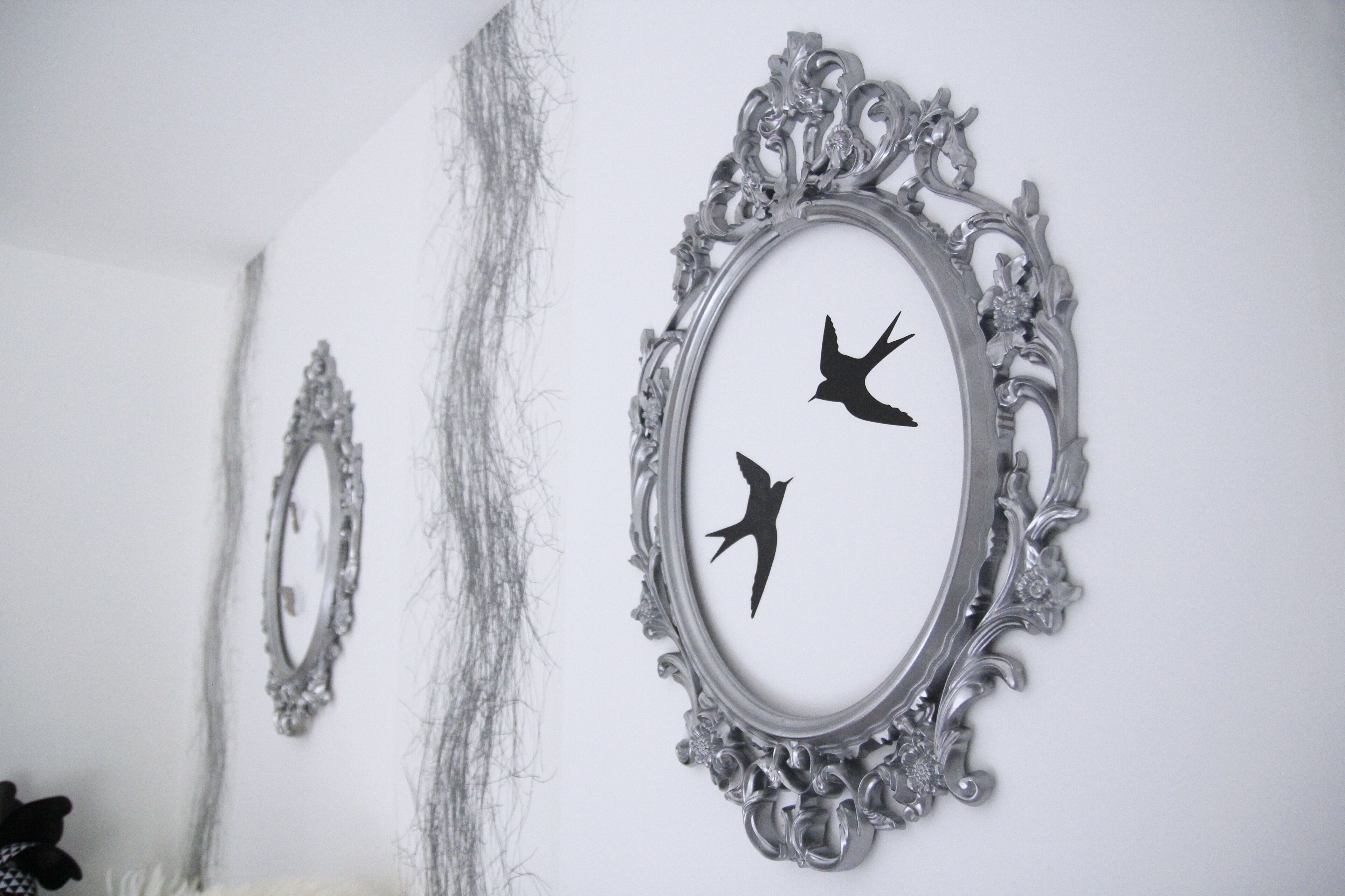 A wall with three ornate silver-framed mirrors.