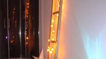 A room with a wooden floor, a glass partition, a star-shaped decoration, a ladder, and a cylindrical object with lights.
