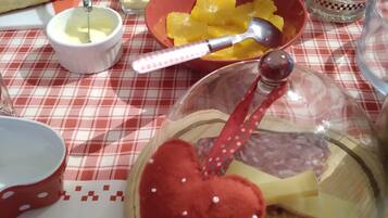A table set with breakfast items including bread, fruit, and a cheese board.