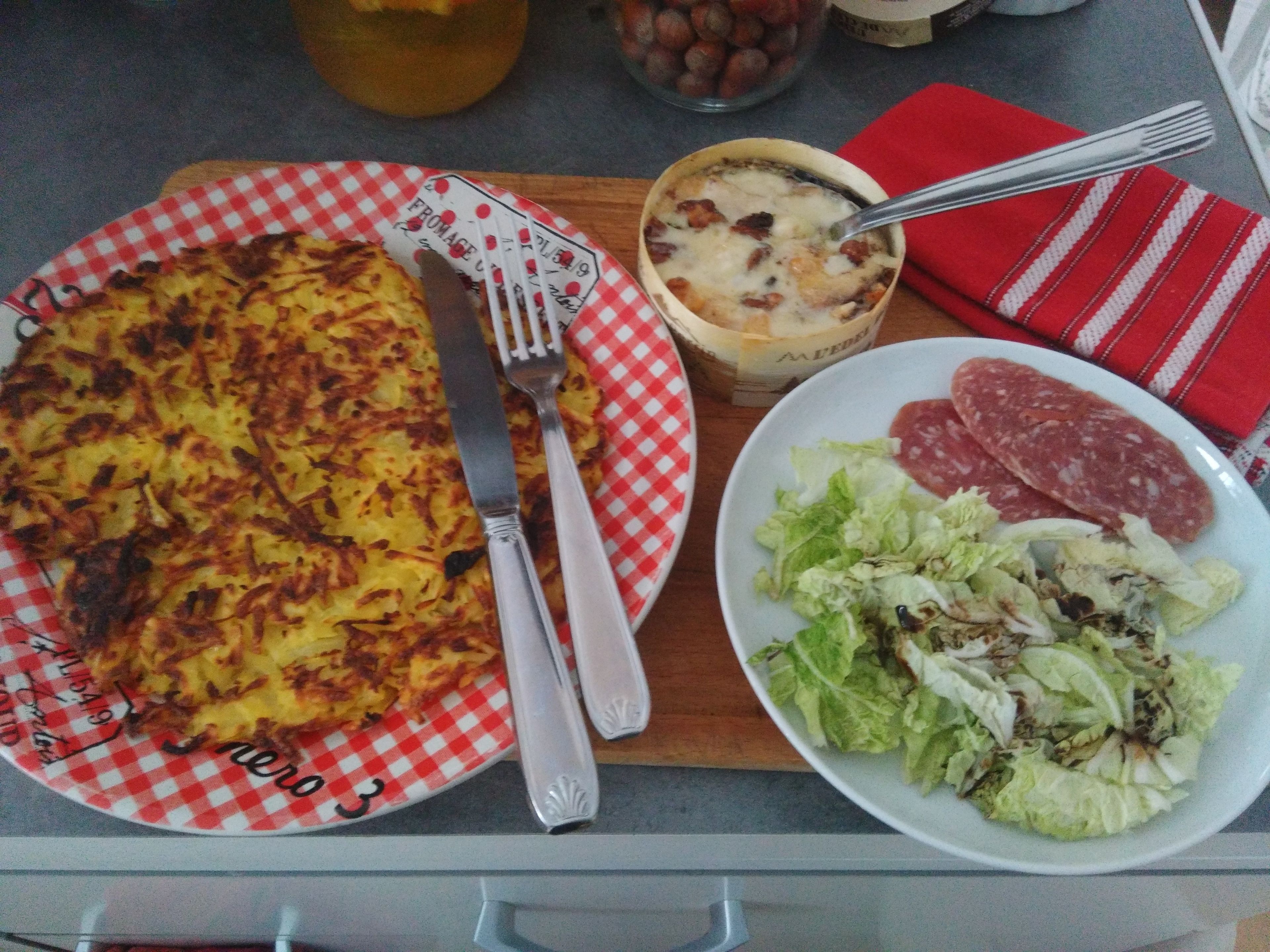 Un pasto con patate, insalata e fette di carne su un tavolo.