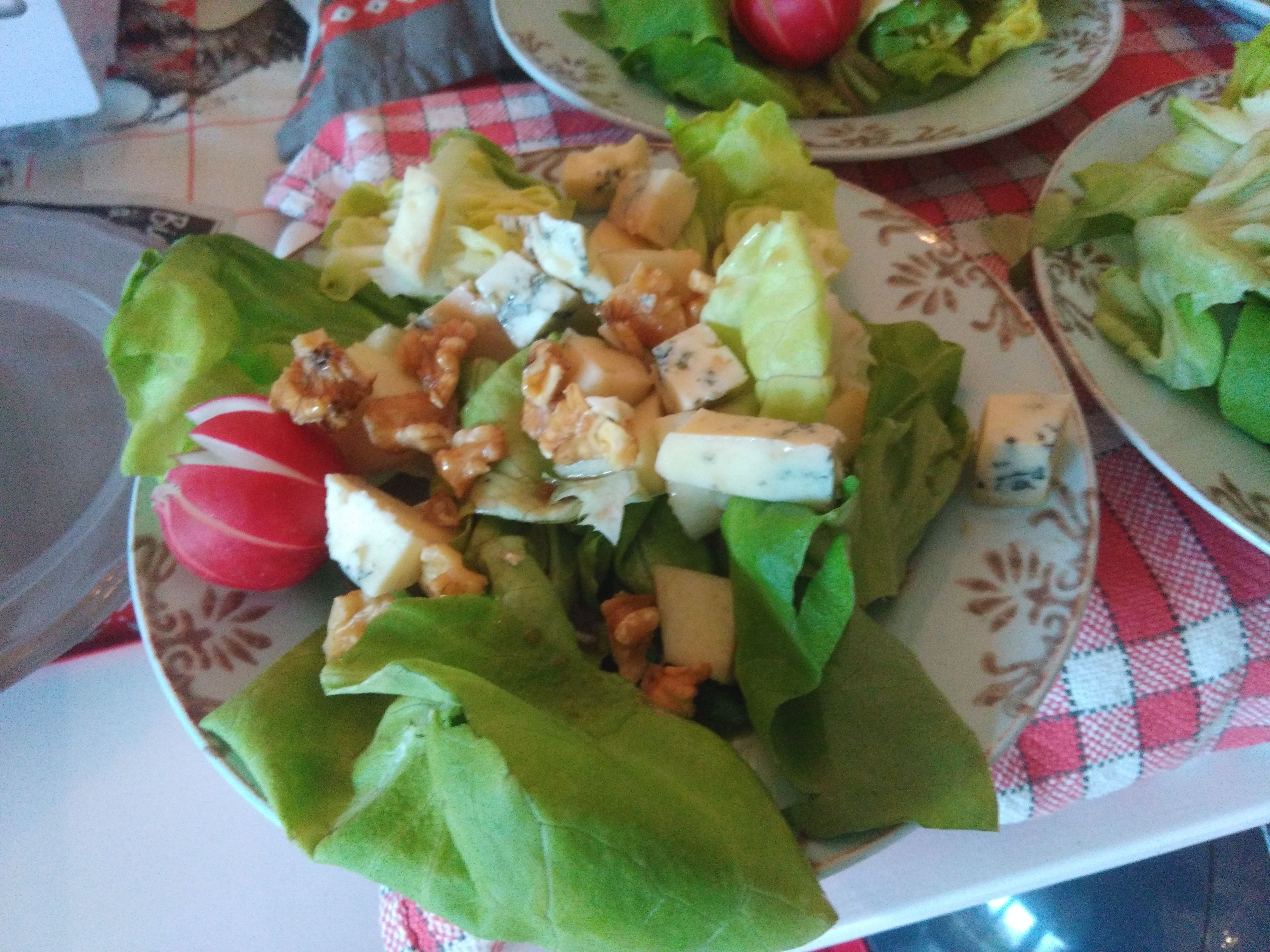 Un plato de ensalada con lechuga, nueces y queso.