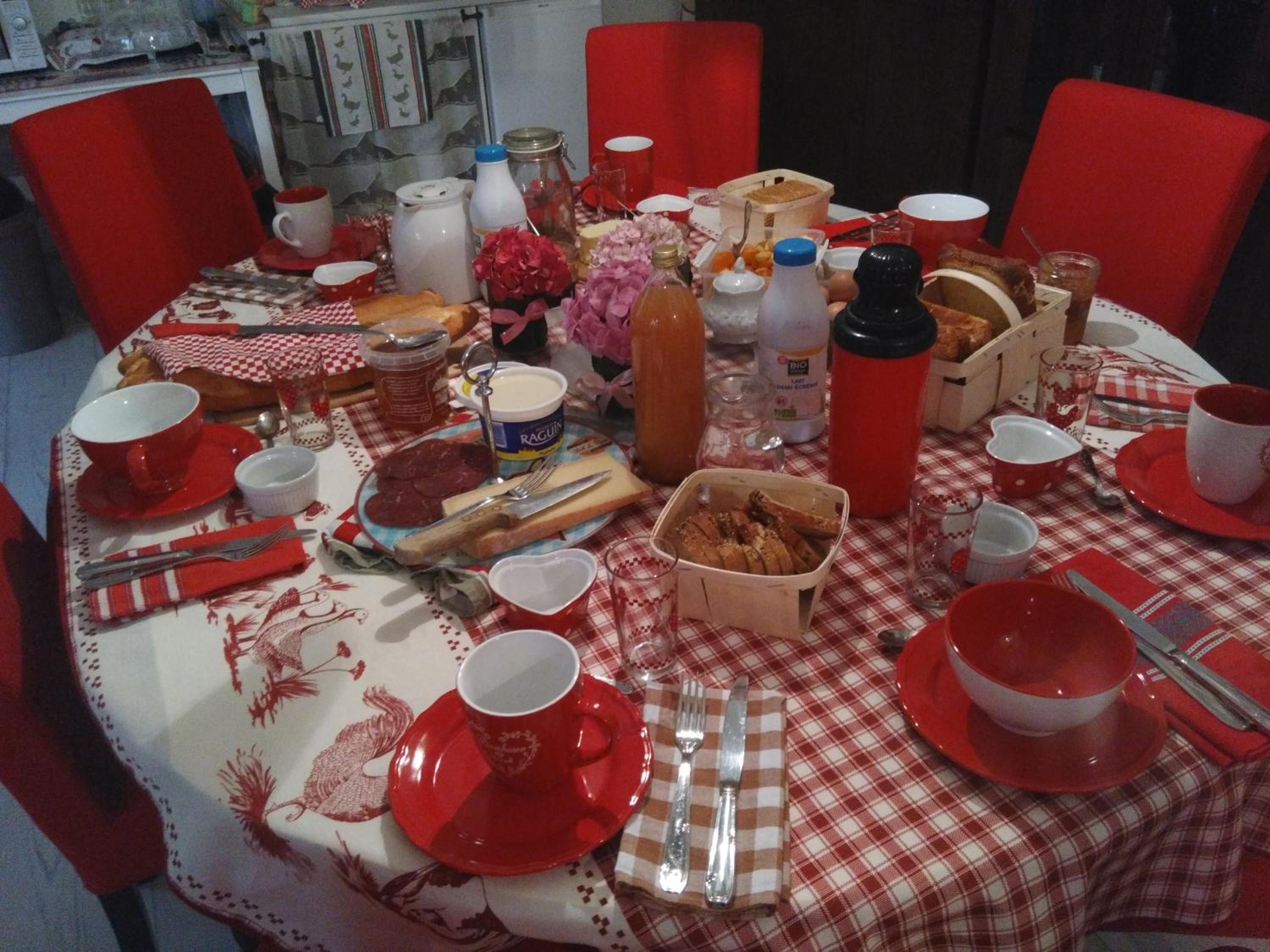 A dining table set with red and white checkered tablecloth, various food items, and utensils.