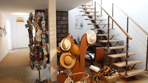A room with a staircase, a hat display, and a bookshelf. - Chambres d'hôtes Souffle Nature  (Montenois)