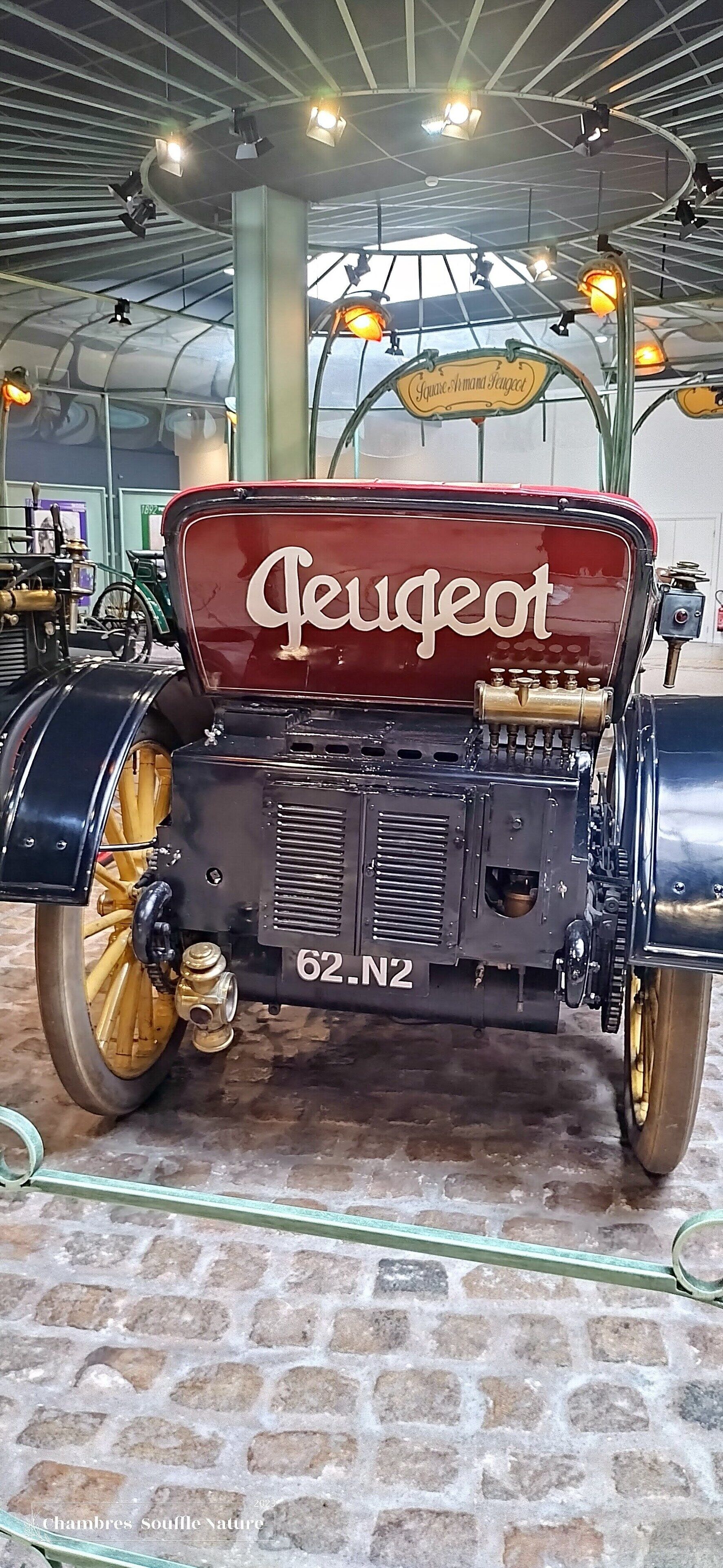Une voiture Peugeot ancienne, dont la plaque d’immatriculation « 62.N2 » est bien visible.