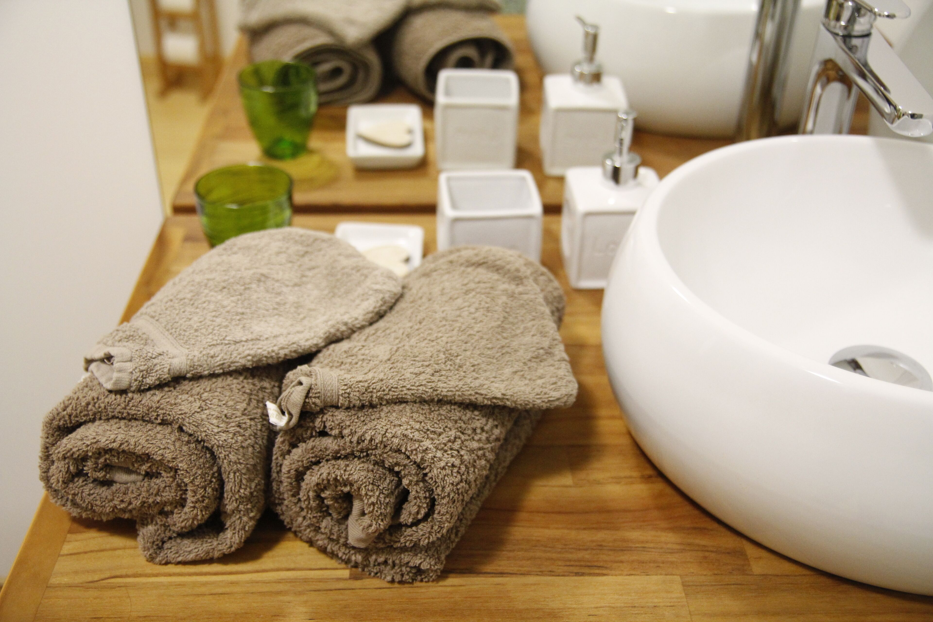 A bathroom with a wooden vanity, a white sink, and neatly folded towels.