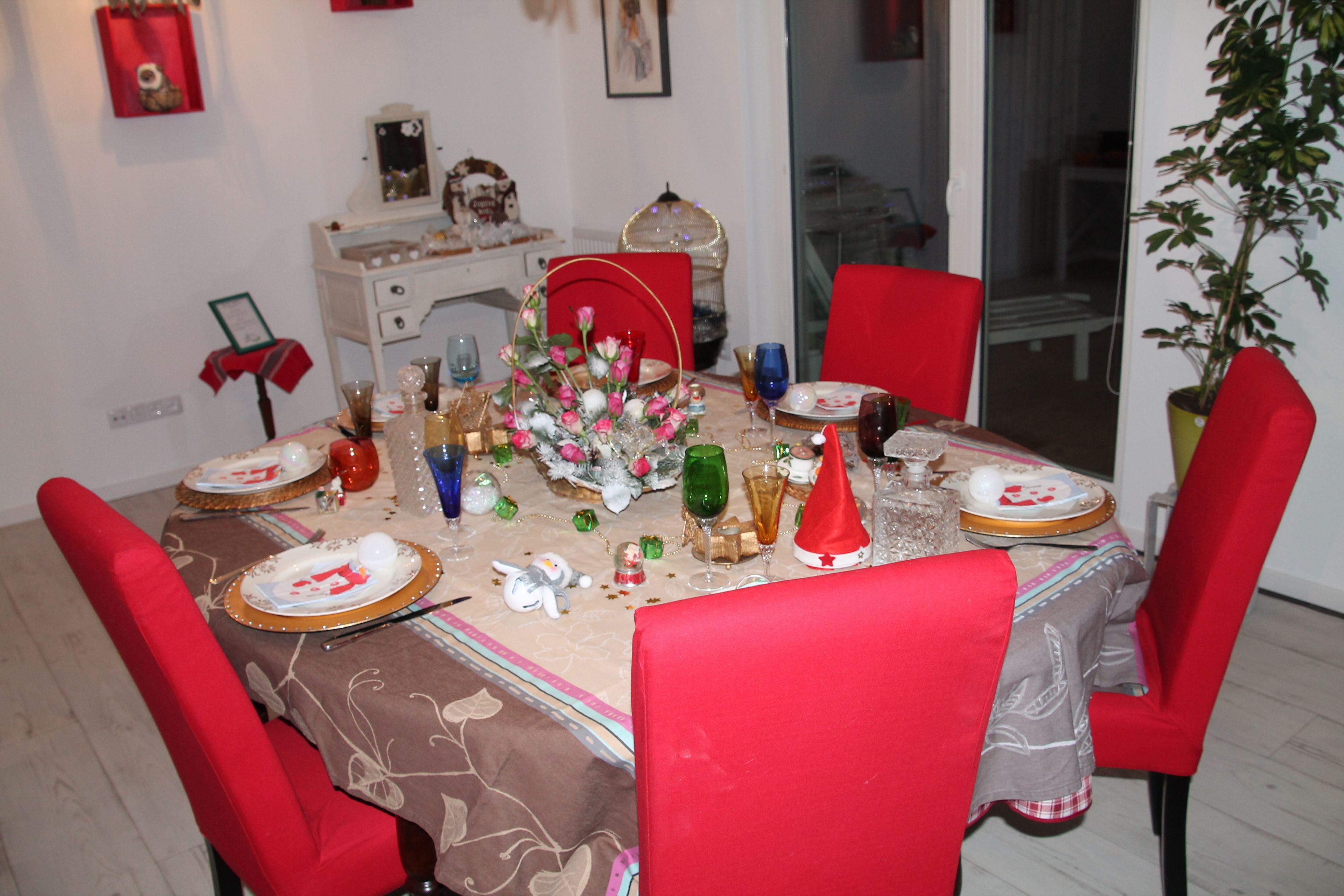 A dining table set with red chairs, a centerpiece, and various dishes and glasses.
