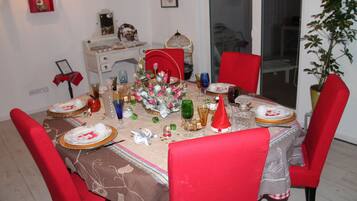 A dining table set with red chairs, a centerpiece, and various dishes and glasses.