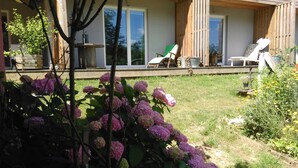 A modern house with a covered patio, a garden with hydrangeas, and a view of the backyard. - Chambres d'hôtes Souffle Nature  (Montenois)