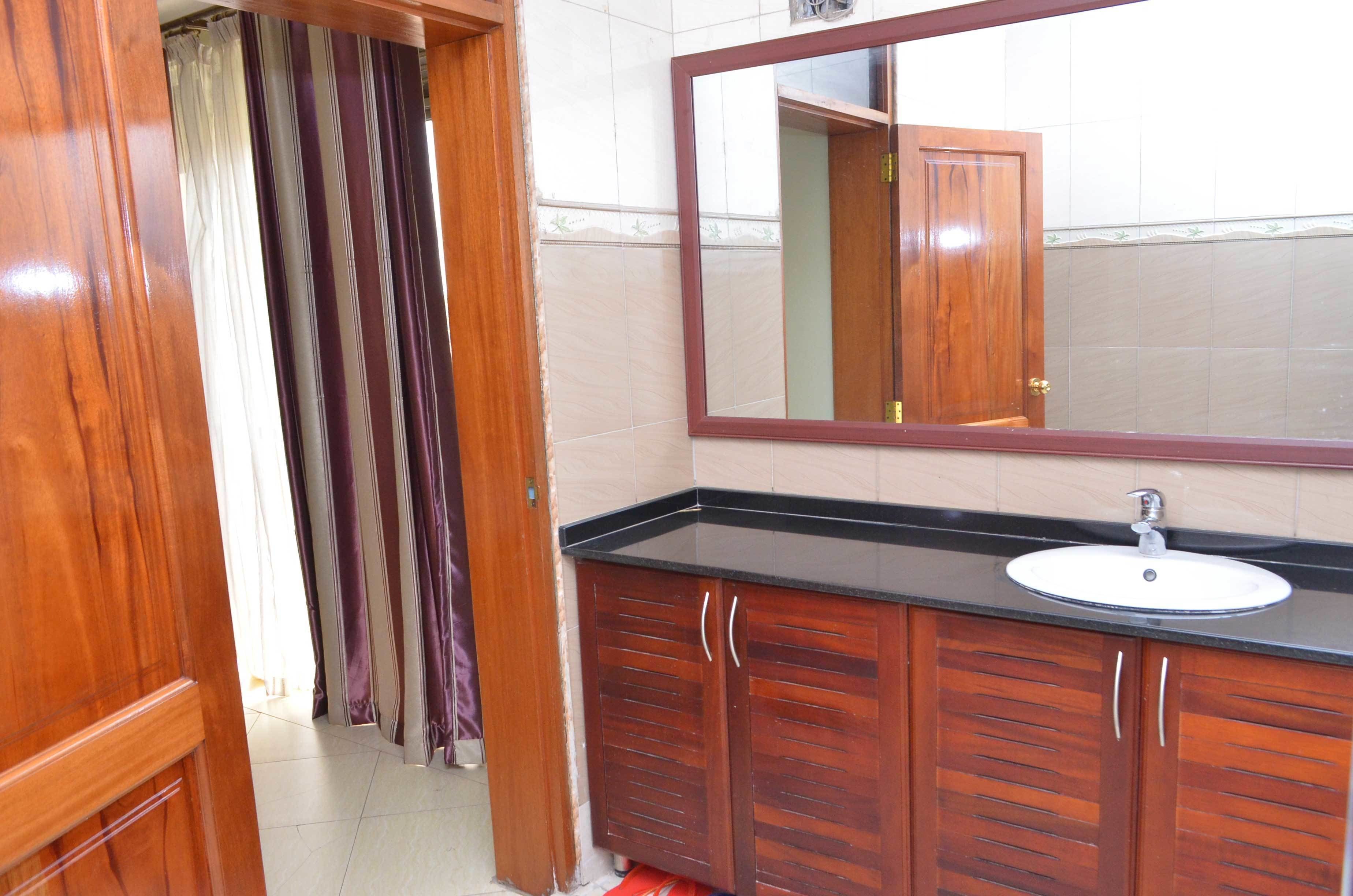 A bathroom with a wooden vanity, a mirror, and a sink.
