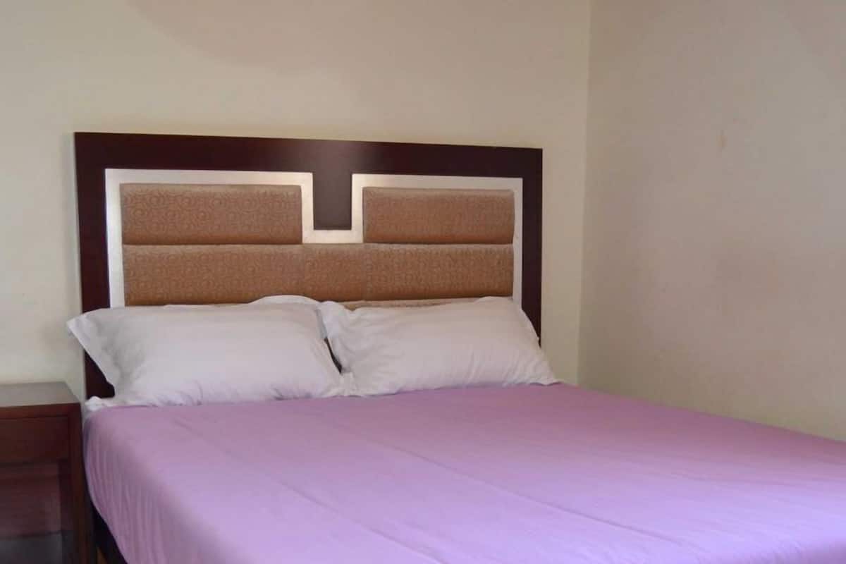 A bed with a wooden headboard, a nightstand, and a purple bedspread.