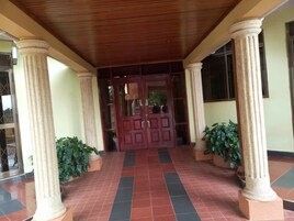 Una entrada techada con techo de madera, grandes columnas y suelo de baldosas.