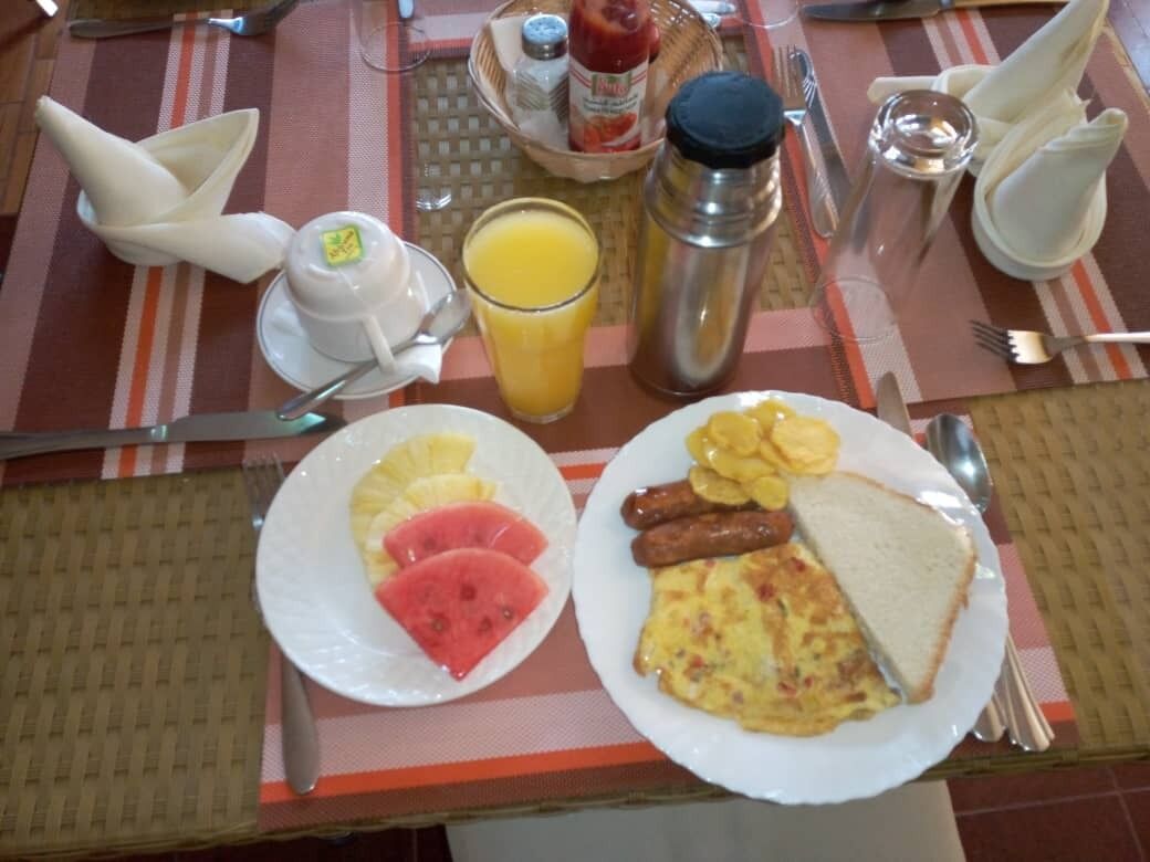 A breakfast setting with plates of food, a glass of orange juice, and a thermos.