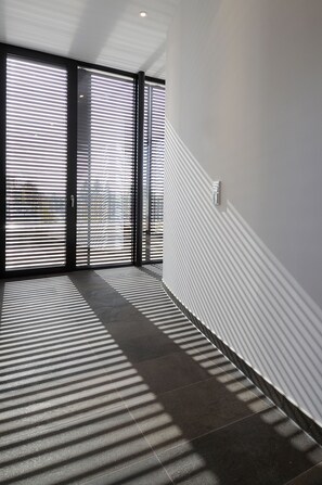 A hallway with a modern design, featuring a tiled floor and a wall with a textured pattern. - Hotel Thalmair (Munich)