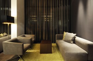 A modern living room with a sofa, two armchairs, a coffee table, and a floor lamp. - Hotel Thalmair (Munich)