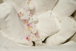 A close-up of a white towel with a decorative orchid garland. - Aparthotel Capitolina (Merida)
