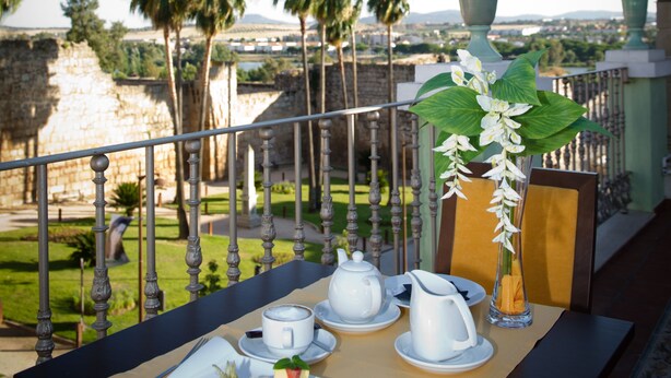 A table set for breakfast with a view of palm trees and a distant cityscape. - Aparthotel Capitolina (Merida)