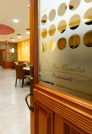 A restaurant entrance with a wooden door and a glass panel featuring circular cutouts. - Aparthotel Capitolina (Merida)