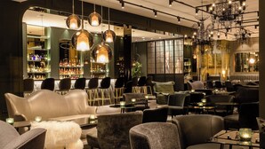 A modern bar area with leather seating, pendant lighting, and a bar stocked with bottles. - Motel One Paris-Porte Dorée (Paris)