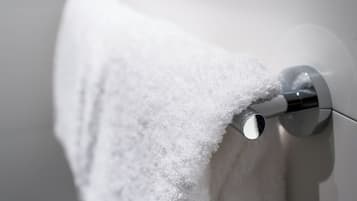 A white towel hanging on a chrome towel bar in a bathroom.