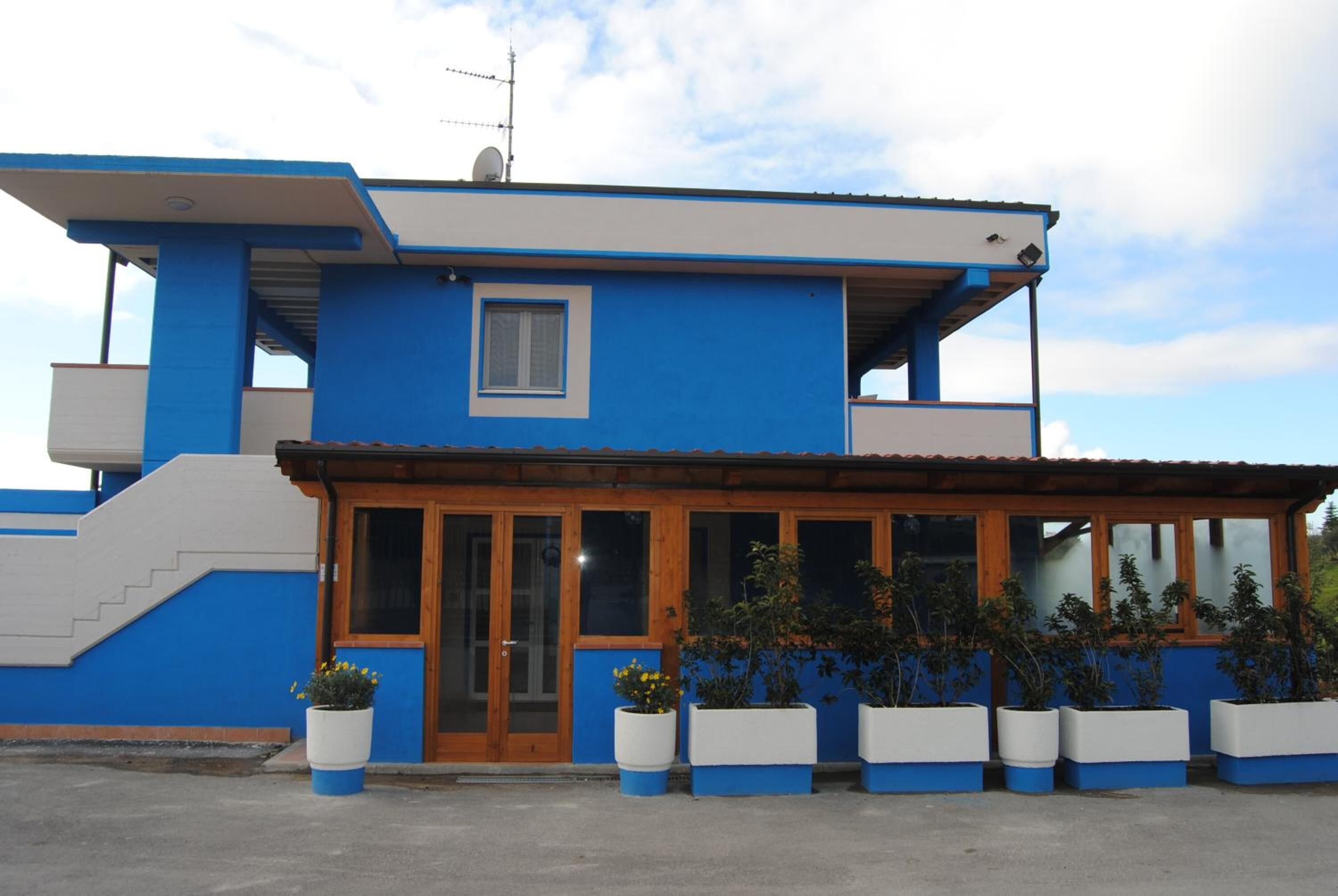 A two-story building with a blue exterior, wooden doors, and a covered porch area.