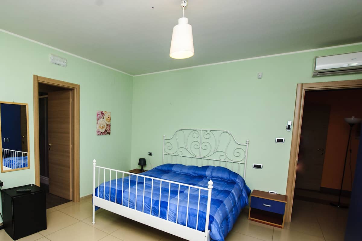 Un dormitorio con cama, armario, escritorio y silla.