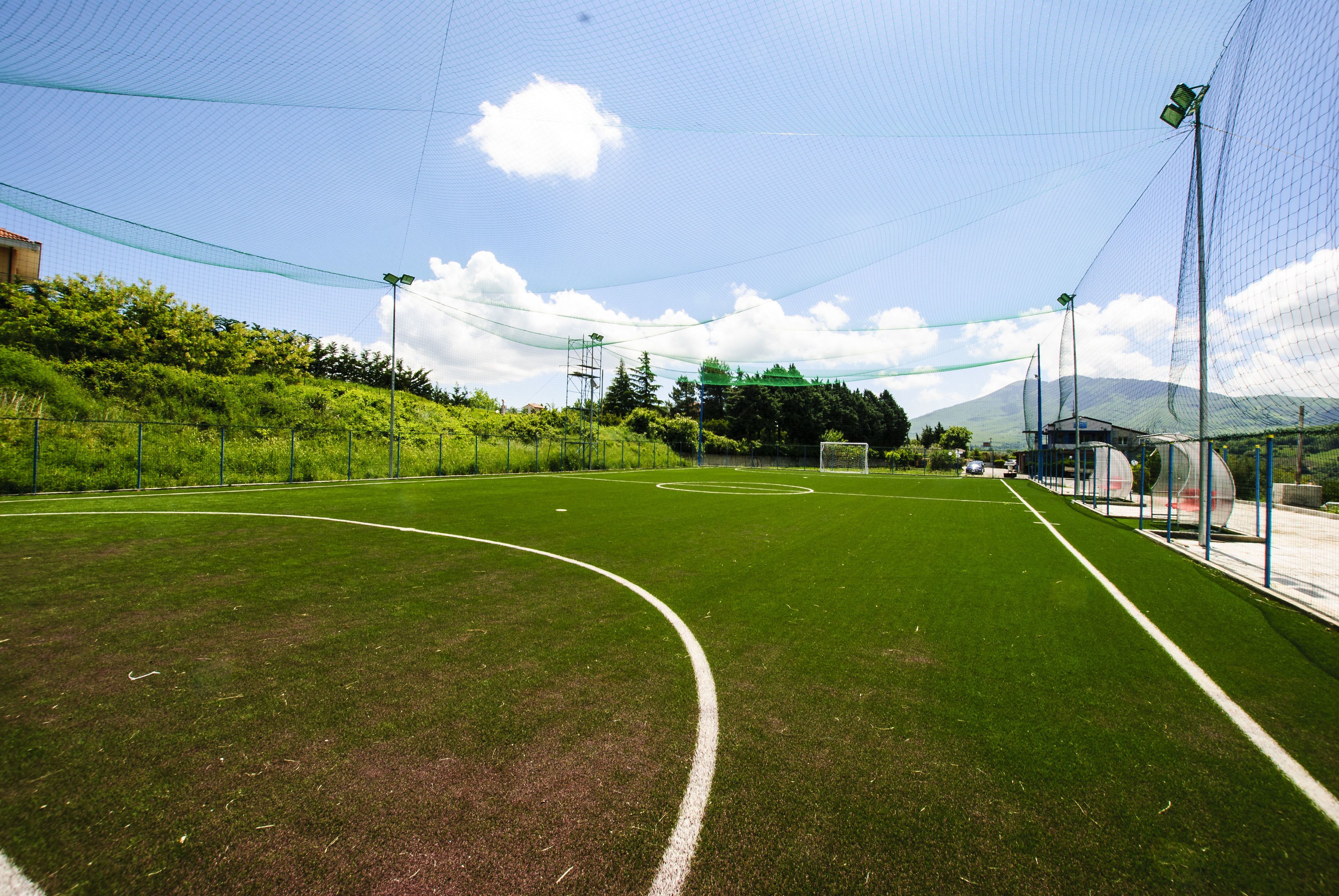 Ein Sportplatz mit einem Tor, umgeben von einem Zaun und Bäumen.