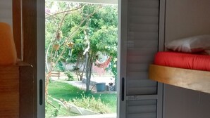 A room with a sliding door leading to a balcony, a bunk bed with pink bedding, and a small rug on the floor. - Hostel Clube da Aventura (Conde)